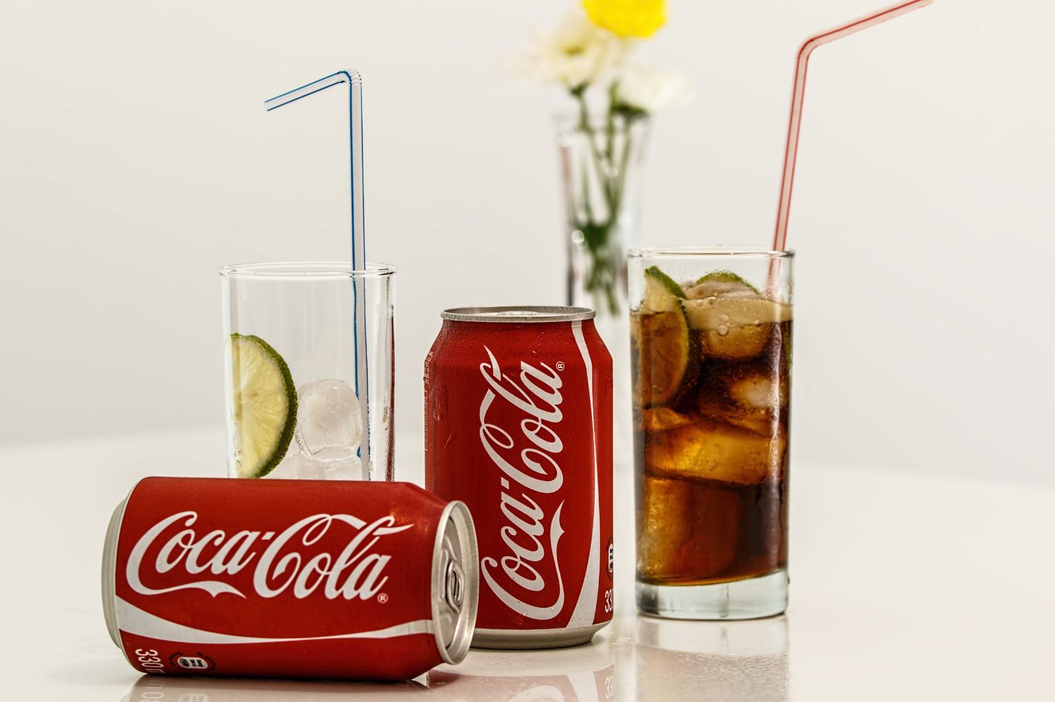 2 blikjes cola naast 2 glazen
